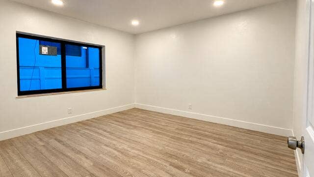 560 NE 15th Avenue, Fort Lauderdale, FL 33301 Recessed lighting, wood-finish flooring, white walls, and a large window with dark trim. Virtually staged.