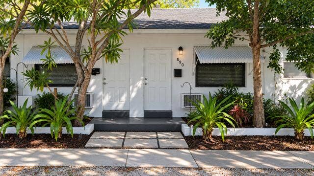 560 NE 15th Avenue, Fort Lauderdale, FL 33301 White stucco exterior with a gray shingle roof, complemented by a gray concrete porch. Virtually staged.