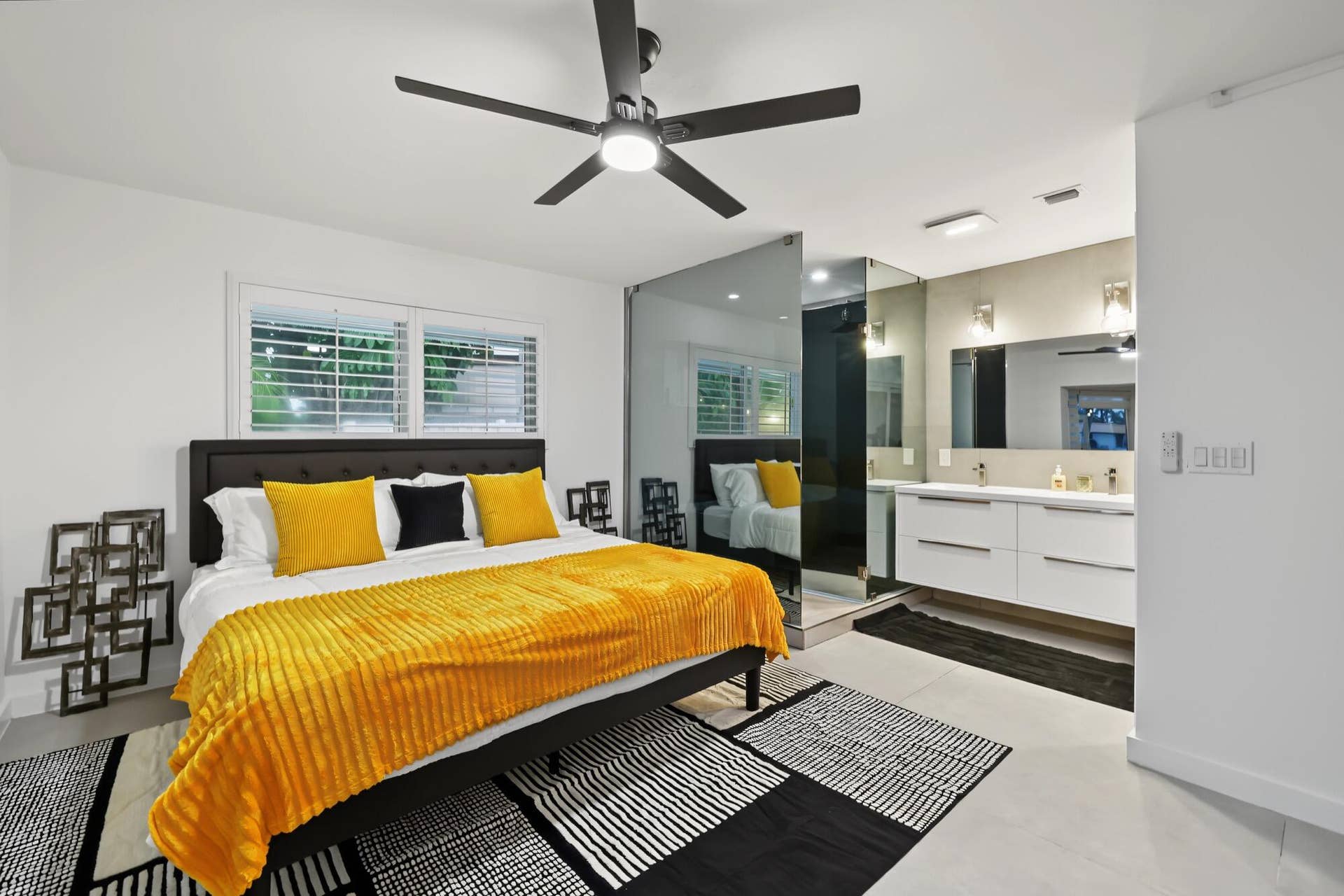 1311 SE 4TH Avenue, Pompano Beach, Pompano Beach, FL 33060 Contemporary room featuring a black ceiling fan, dual windows with plantation shutters, a floating double vanity with rectangular sinks, and a mirrored wall partition