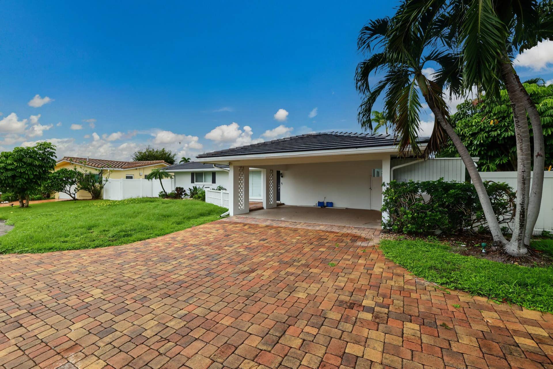 1311 SE 4TH Avenue, Pompano Beach, Pompano Beach, FL 33060 Paved driveway with multi-tone brick pavers, carport, and lush tropical landscaping