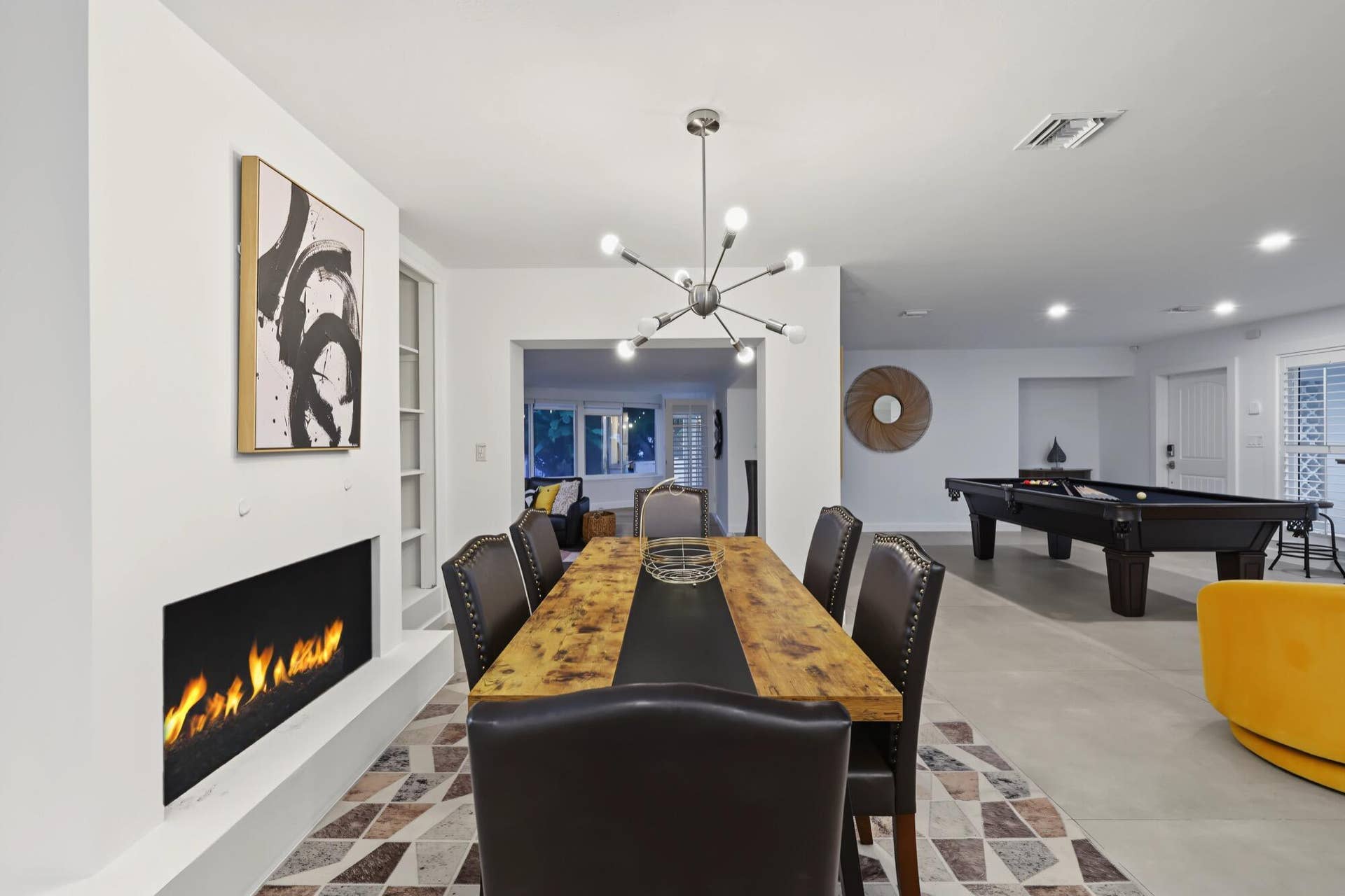 1311 SE 4TH Avenue, Pompano Beach, Pompano Beach, FL 33060 Linear fireplace feature with a light-toned hearth, wood-finish dining table, and a contemporary sputnik chandelier