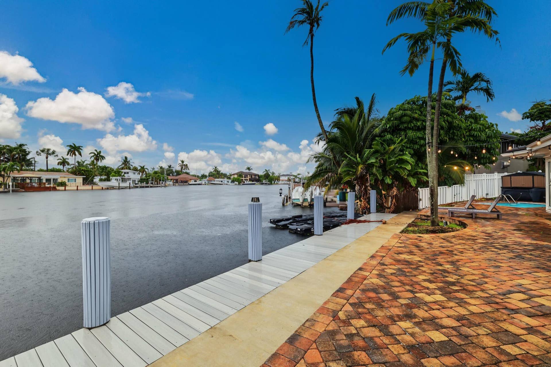 1311 SE 4TH Avenue, Pompano Beach, Pompano Beach, FL 33060 Waterfront property featuring a private dock, brick paver patio, lush tropical landscaping, and a pool with an attached spa