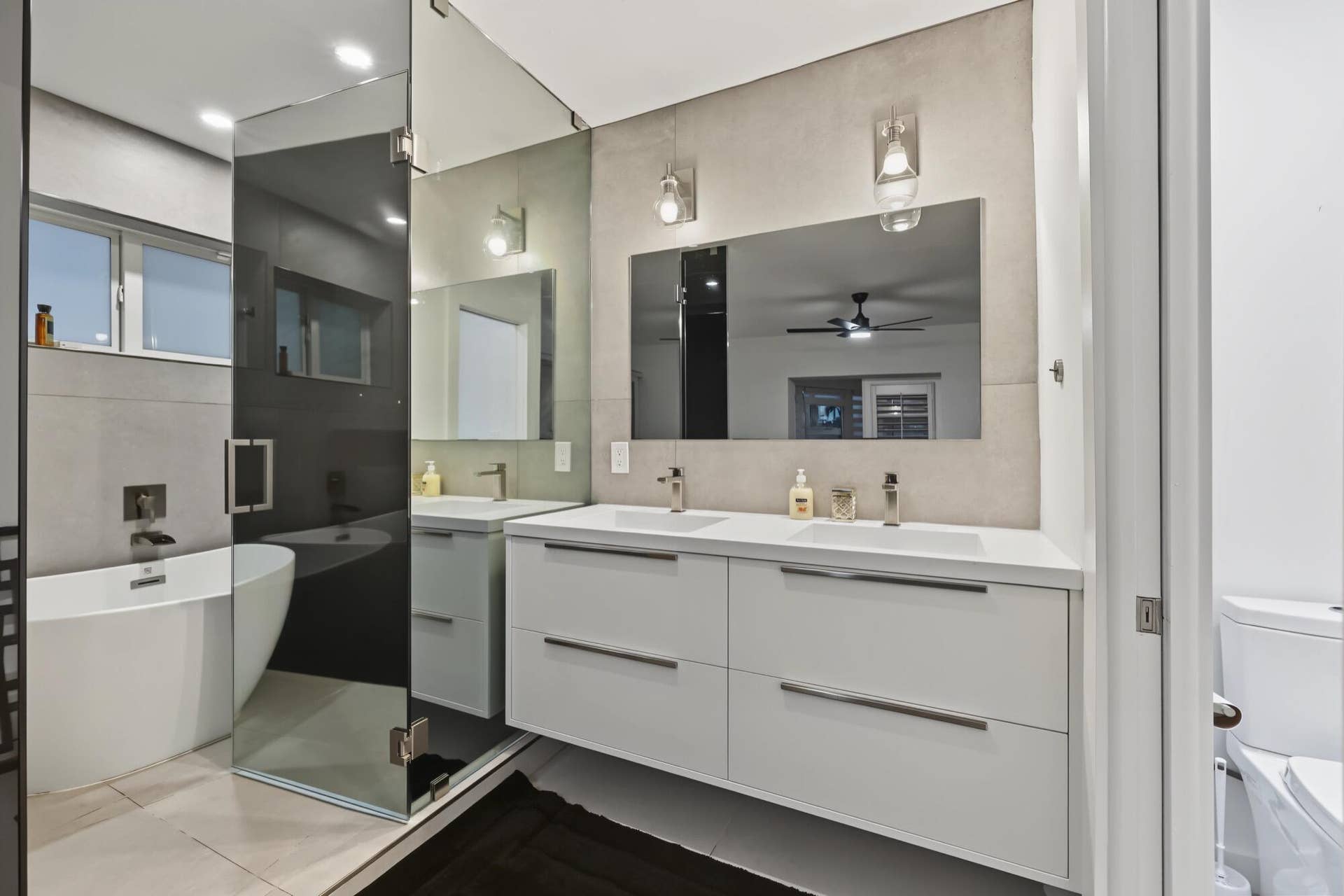 1311 SE 4TH Avenue, Pompano Beach, Pompano Beach, FL 33060 Modern bathroom featuring a floating dual vanity with integrated sinks, a freestanding tub, and a glass-enclosed shower