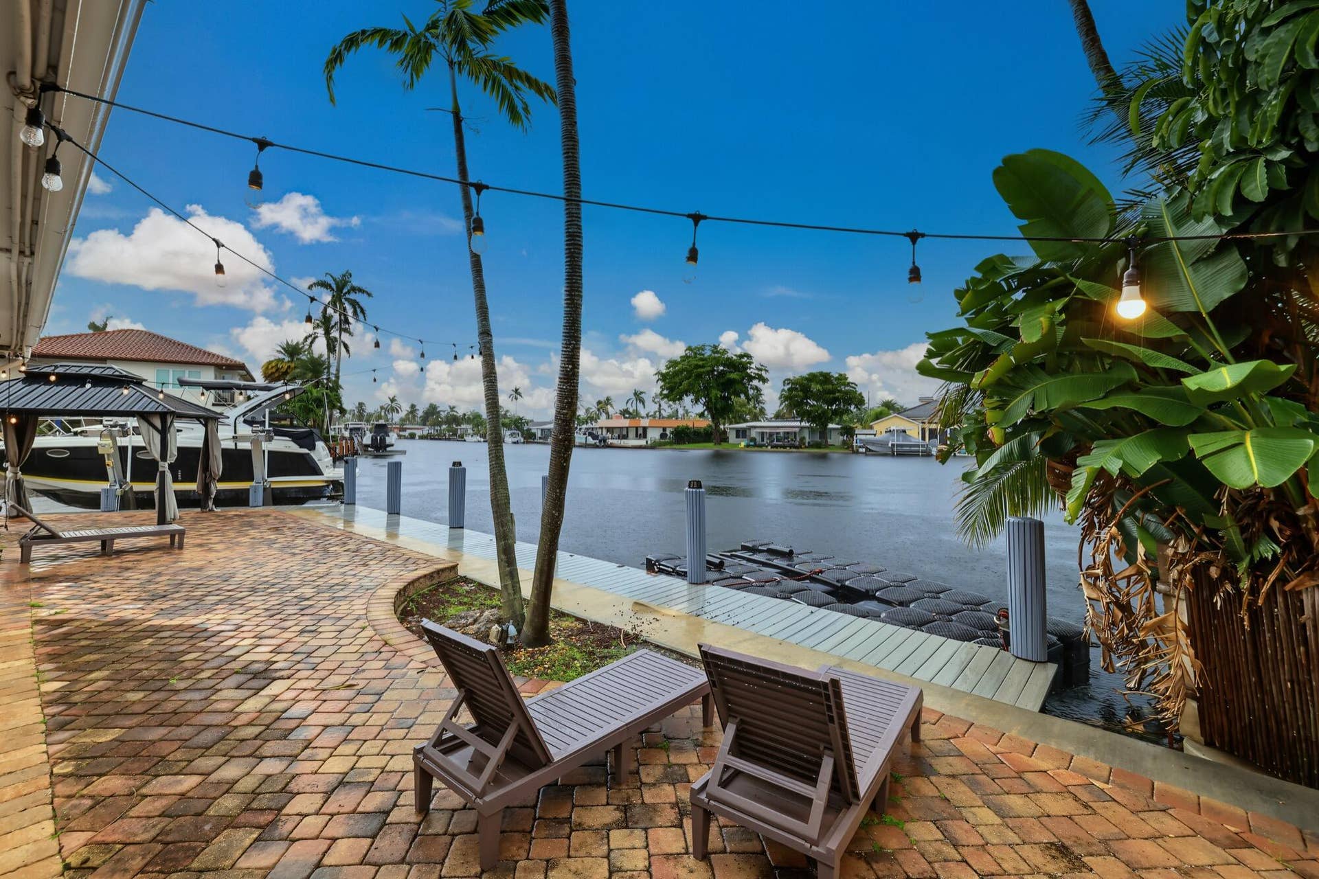 1311 SE 4TH Avenue, Pompano Beach, Pompano Beach, FL 33060 Waterfront property featuring a brick paver patio, mature palm trees, and a private dock