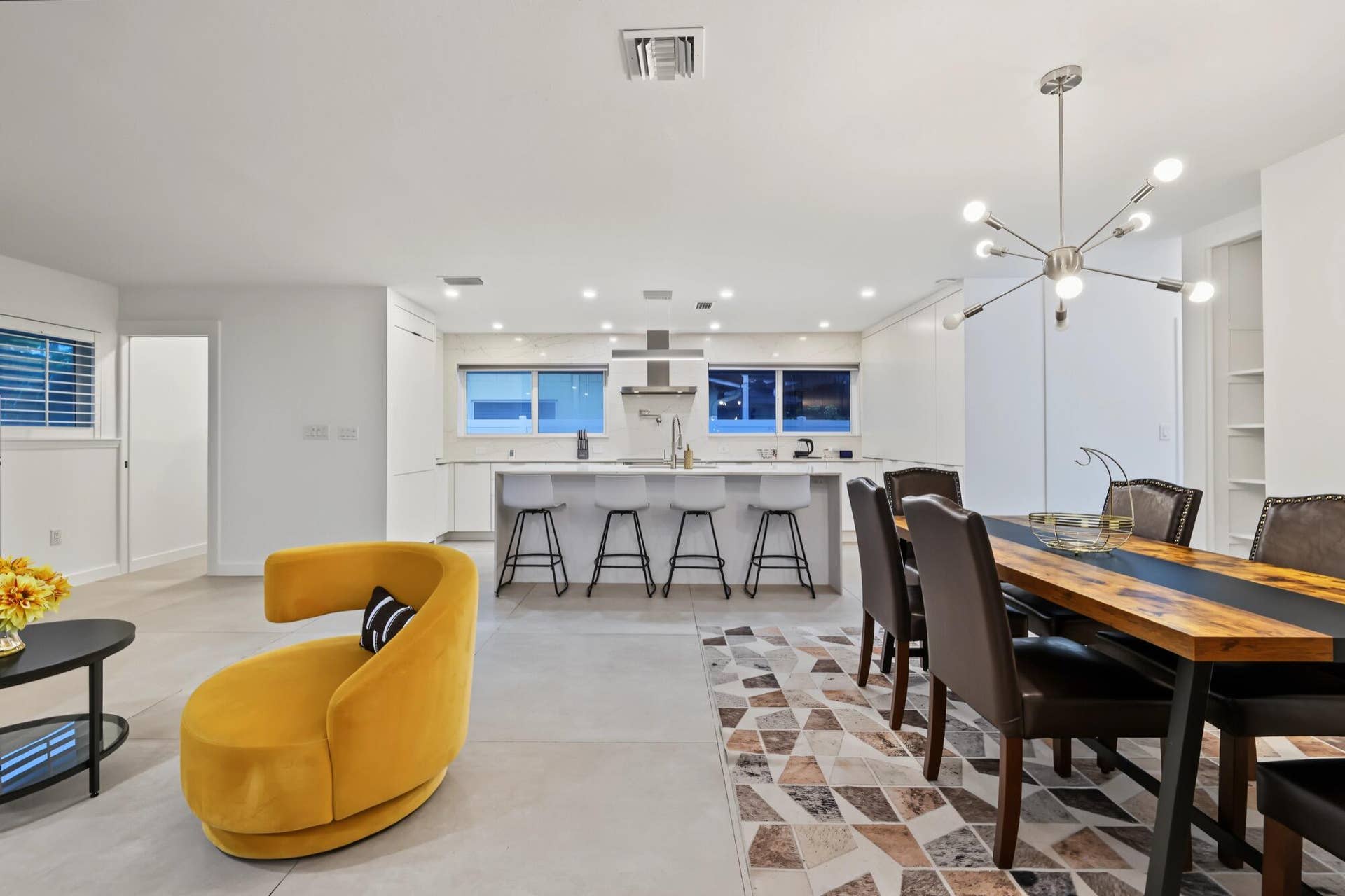 1311 SE 4TH Avenue, Pompano Beach, Pompano Beach, FL 33060 Open-concept living space featuring a modern kitchen with an island, a dining area with a contemporary chandelier, and light-toned flooring throughout