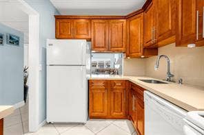 Kitchen featuring wood-finish cabinetry, light-toned countertops, and a stainless steel gooseneck faucet