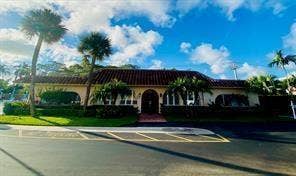 Mediterranean-inspired architecture with a red tile roof, stucco exterior, arched entry, and mature landscaping