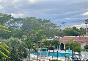 Outdoor swimming pool with surrounding lounge chairs, lush palm trees, and mature landscaping