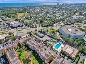 Aerial perspective featuring a community with multiple buildings, a swimming pool, and surrounding green spaces