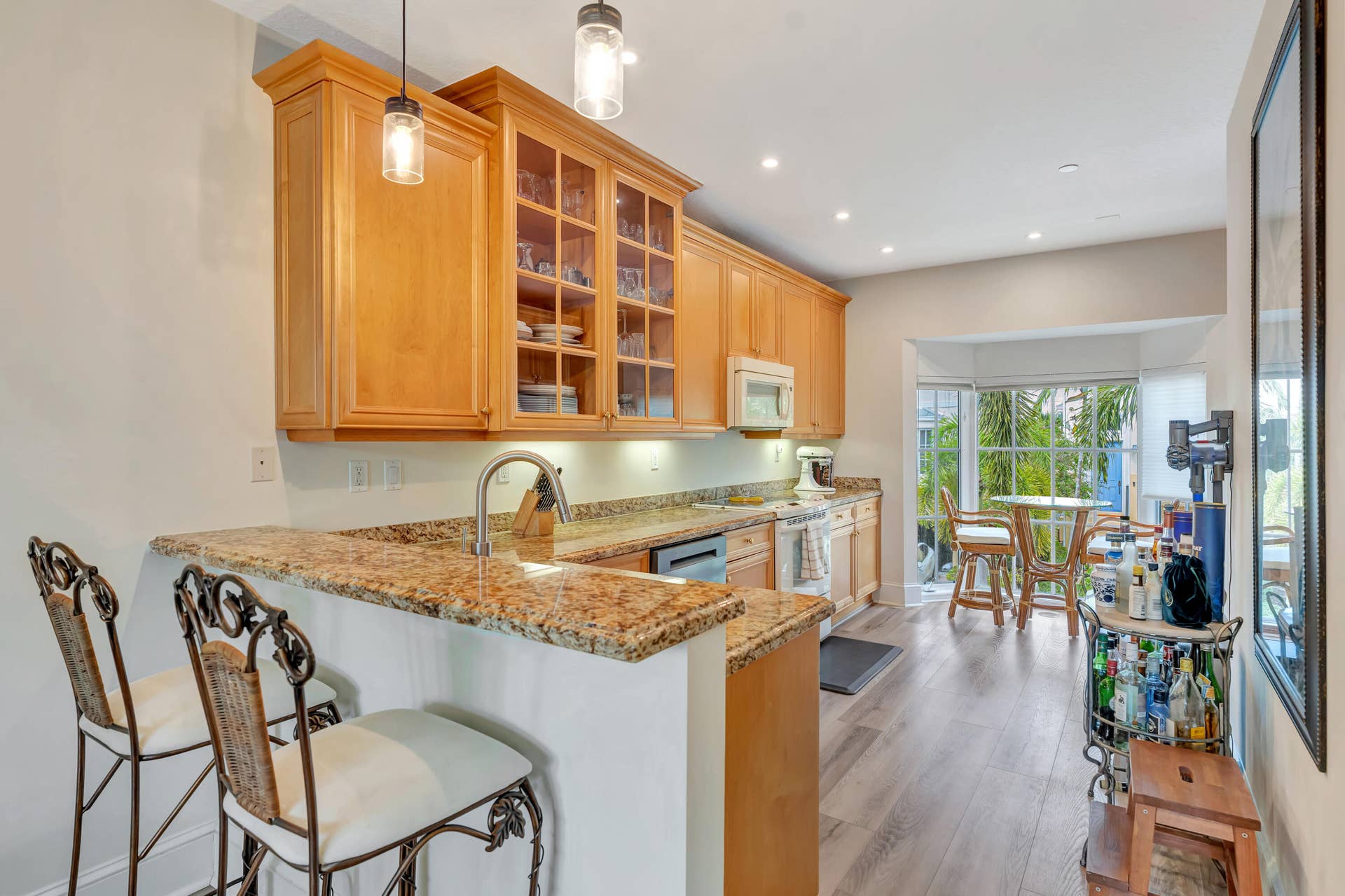 471 JUNO DUNES Way, Juno Beach, FL 33408 Light wood-finish cabinetry with glass-front display cabinets, granite countertops, stainless steel sink with gooseneck faucet, and recessed lighting