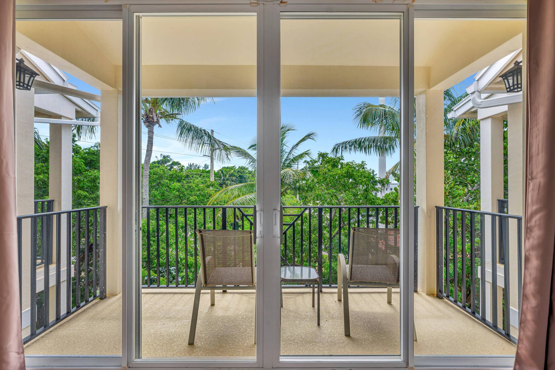 471 JUNO DUNES Way, Juno Beach, FL 33408 Sliding glass doors opening to a private balcony with black metal railings, a textured flooring surface, and exterior wall sconces