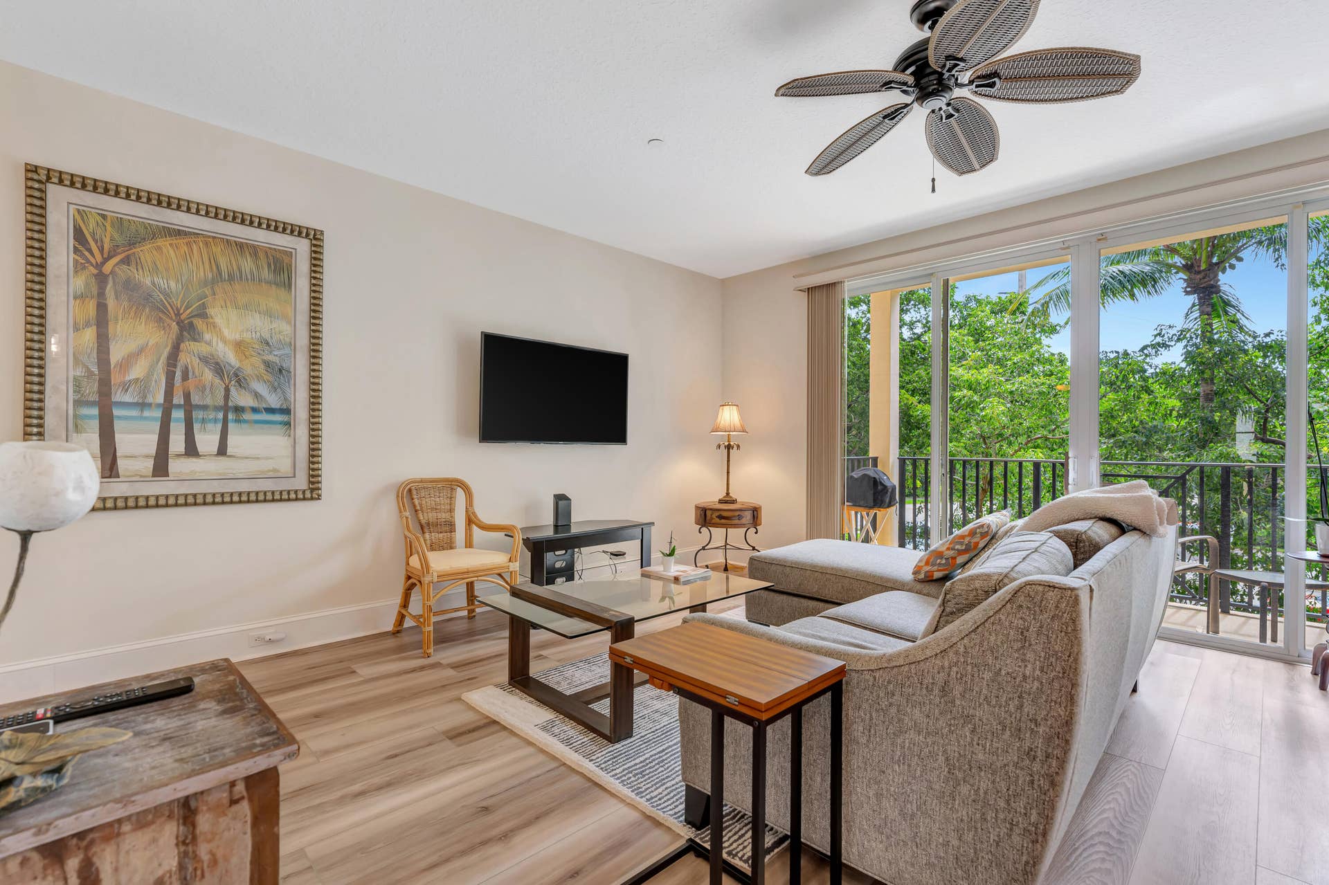 471 JUNO DUNES Way, Juno Beach, FL 33408 Spacious living area featuring wood-finish flooring, a ceiling fan, and sliding glass doors opening to an outdoor balcony with black railings