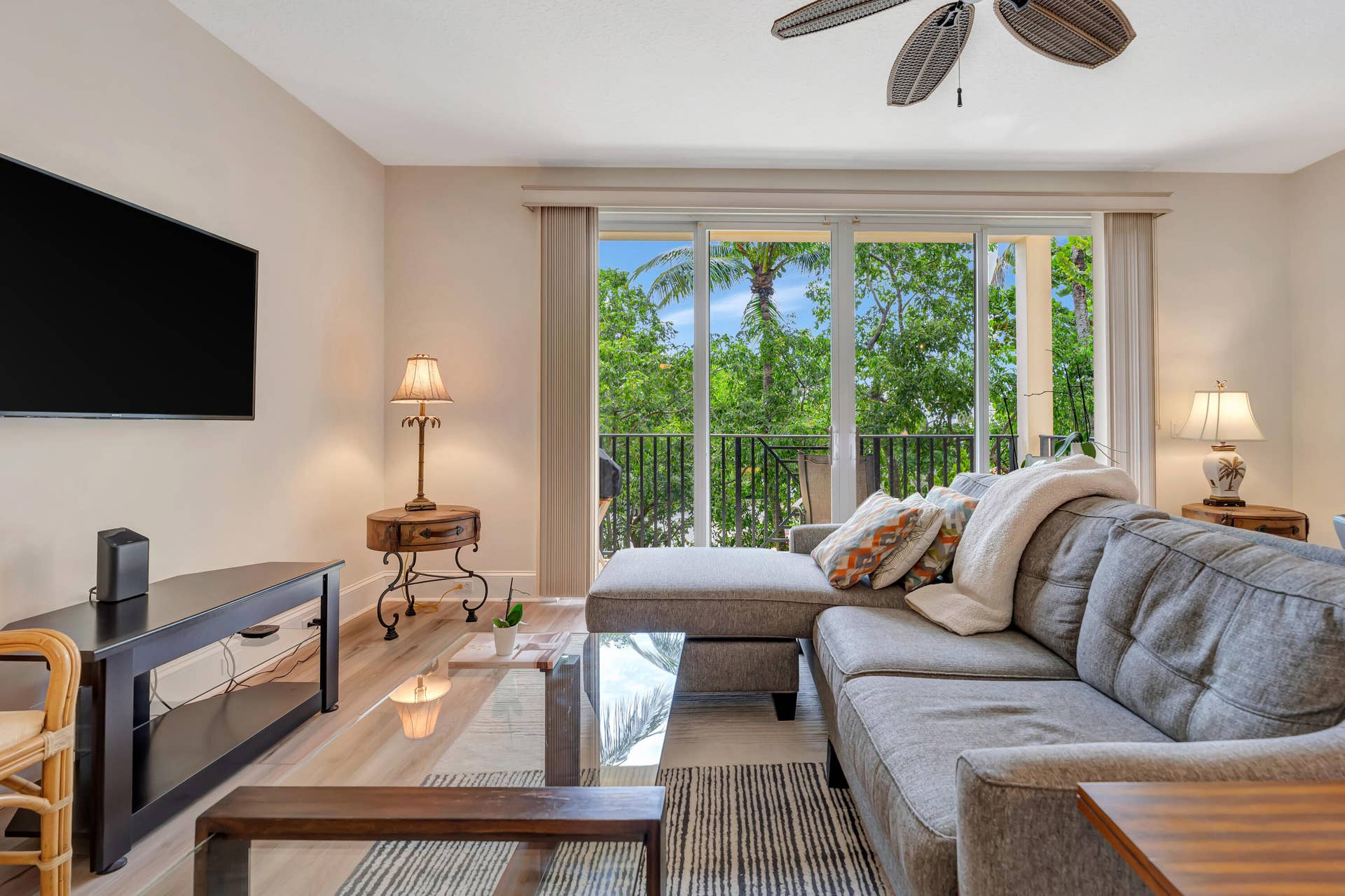 471 JUNO DUNES Way, Juno Beach, FL 33408 Wood-finish flooring, ceiling fan, and sliding glass doors opening to an exterior balcony with a black metal railing