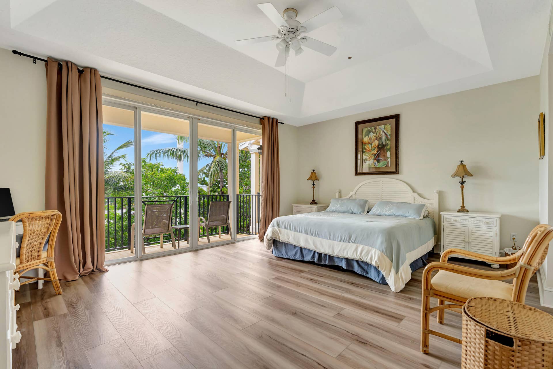 471 JUNO DUNES Way, Juno Beach, FL 33408 Tray ceiling, wood-finish flooring, sliding glass doors, private balcony with black wrought iron railing, and a ceiling fan