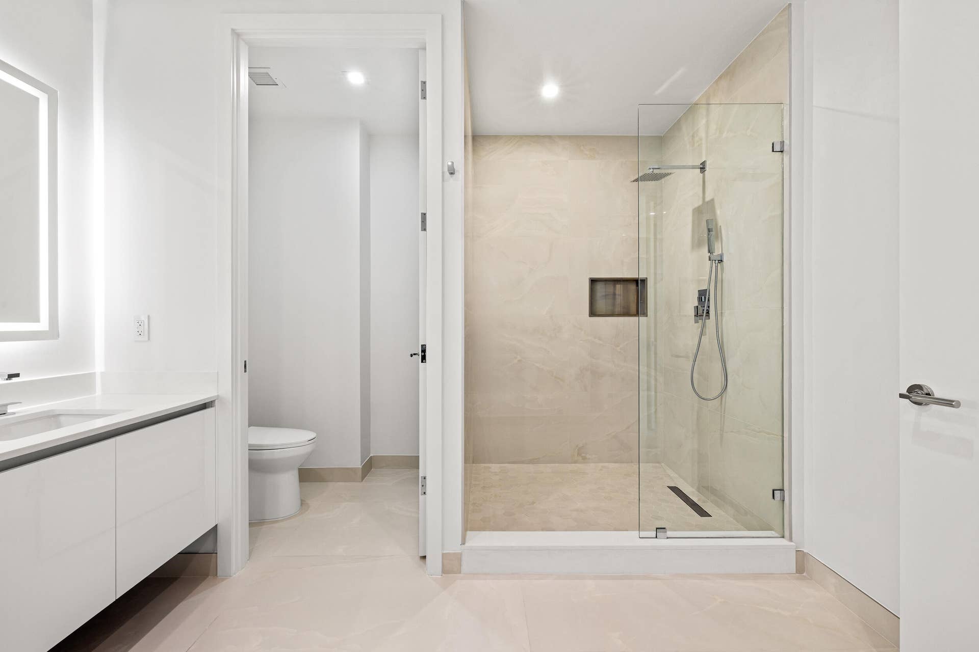 220 Lake Shore Drive, #704, Lake Park, FL 33403 Master Bath - Modern bathroom featuring a frameless glass shower enclosure, a rainfall showerhead, and a vanity with an illuminated mirror