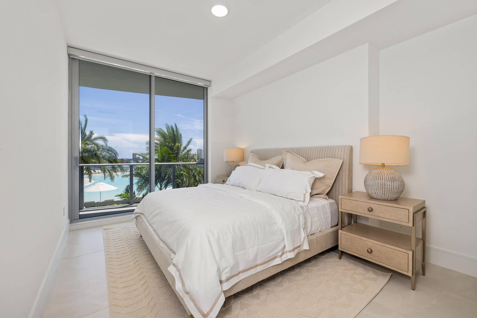 220 Lake Shore Drive, #704, Lake Park, FL 33403 Floor-to-ceiling glass doors, white tile flooring, recessed ceiling lighting, and a neutral upholstered headboard