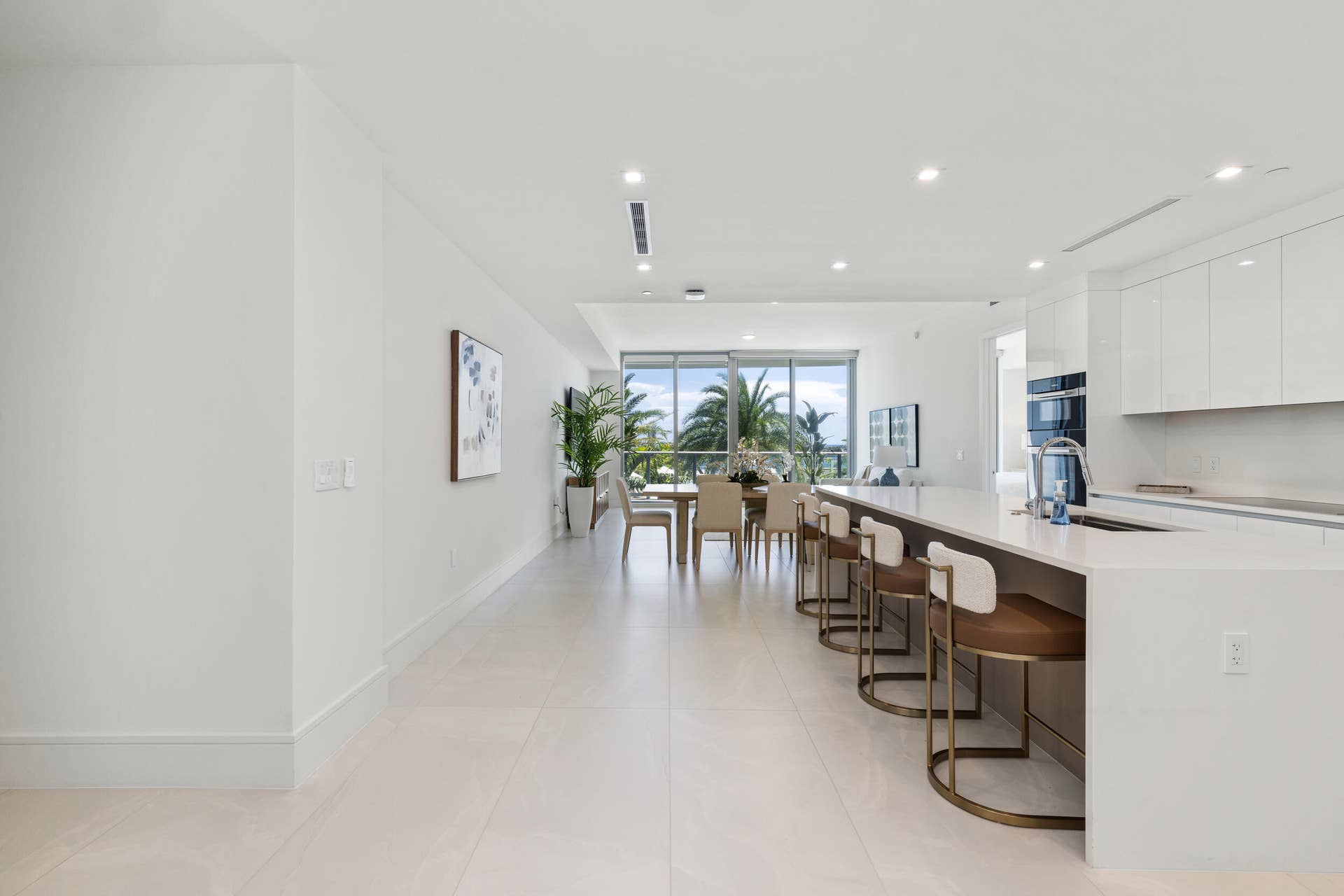 220 Lake Shore Drive, #704, Lake Park, FL 33403 Contemporary open concept living area with light-toned flooring, recessed lighting, expansive floor-to-ceiling windows, and a kitchen island with integrated seating
