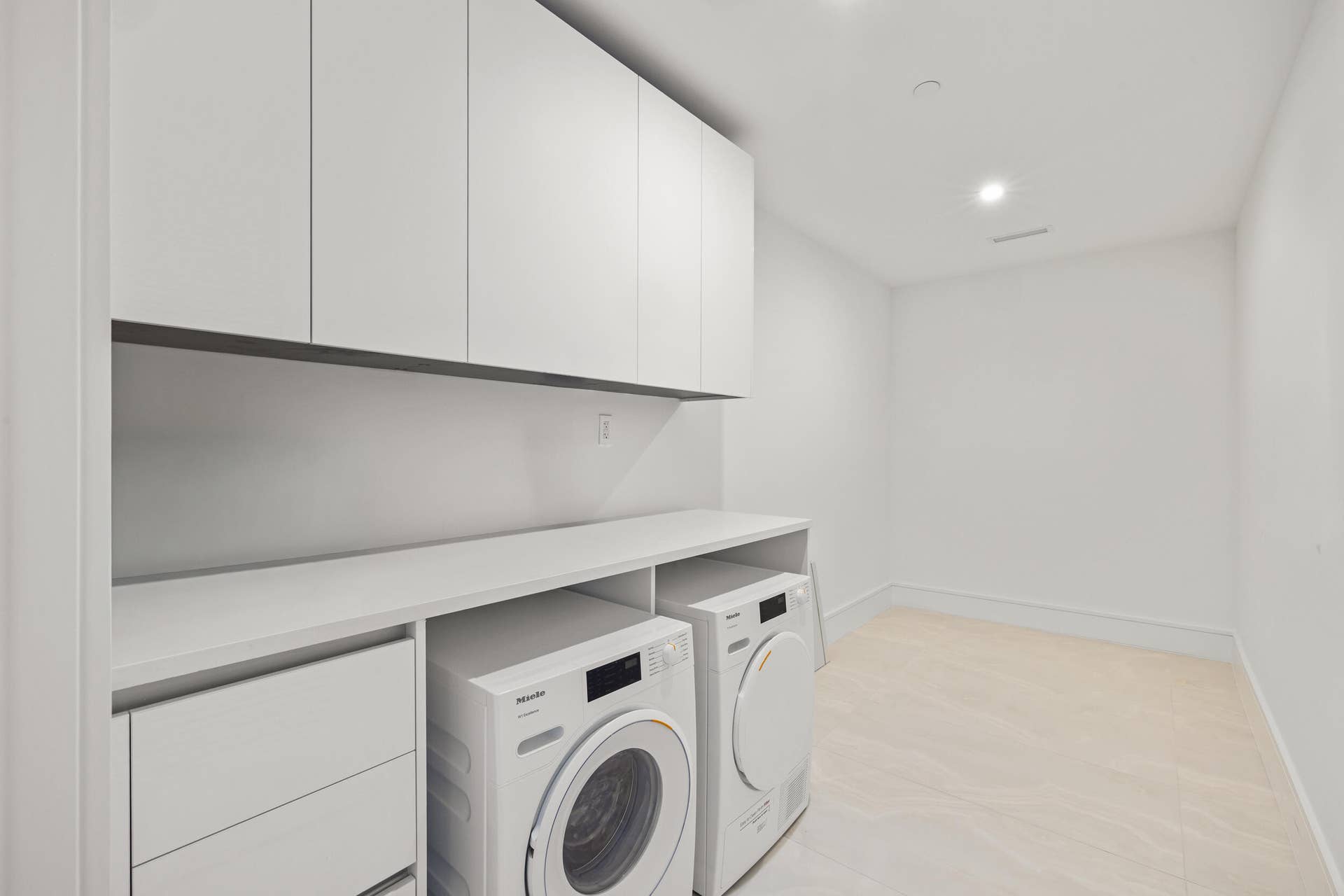 220 Lake Shore Drive, #704, Lake Park, FL 33403 Integrated laundry appliances with extensive white cabinetry, a spacious countertop, and light-toned flooring