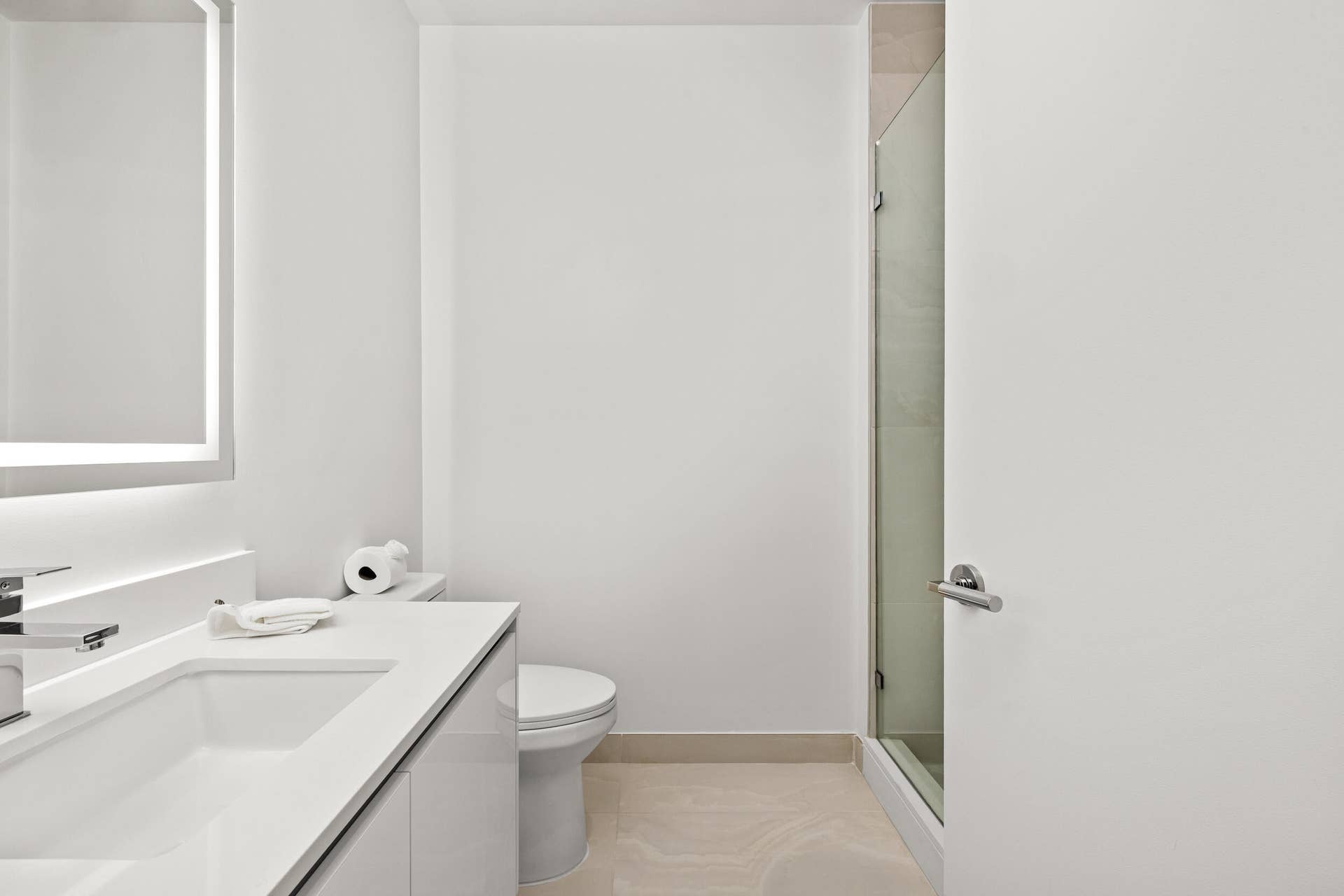 220 Lake Shore Drive, #704, Lake Park, FL 33403 Modern vanity with integrated sink, chrome faucet, illuminated mirror, and glass-enclosed shower