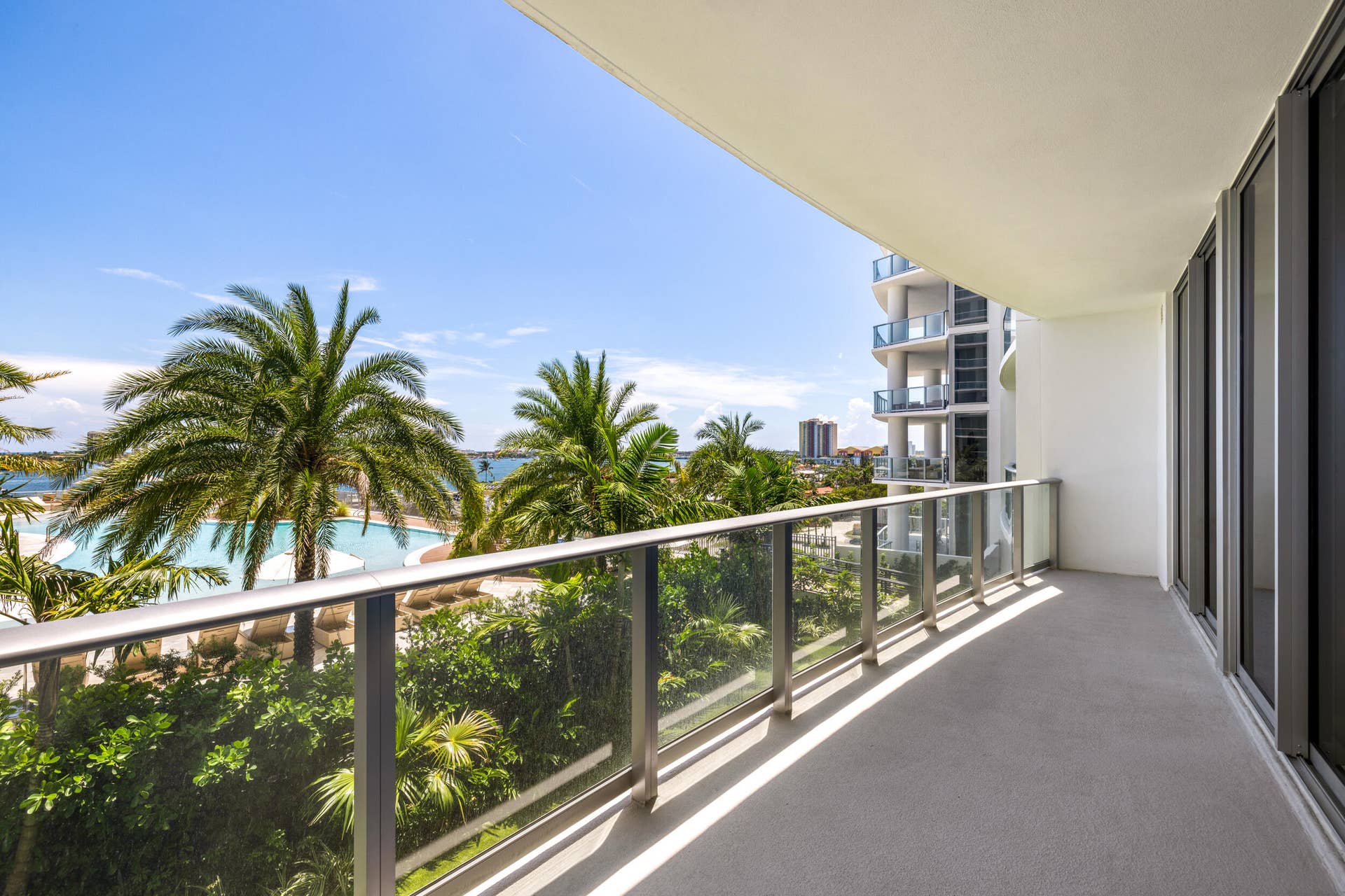 220 Lake Shore Drive, #704, Lake Park, FL 33403 Expansive private balcony with glass railing, concrete flooring, and direct access to interior spaces through large glass doors