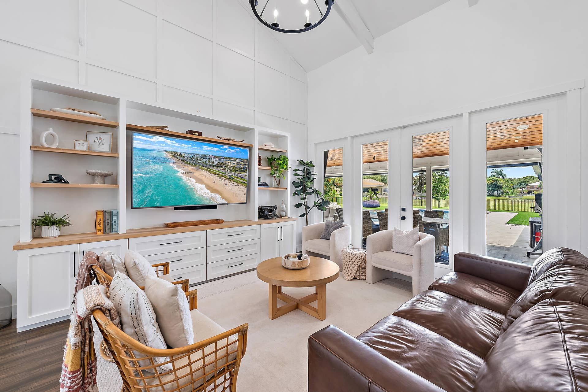 6204 SAND PINE Court, Jupiter, Jupiter, FL 33458 Vaulted ceiling, built-in entertainment center with wood-finish countertops, wall paneling, and multiple glass French doors leading to a covered patio