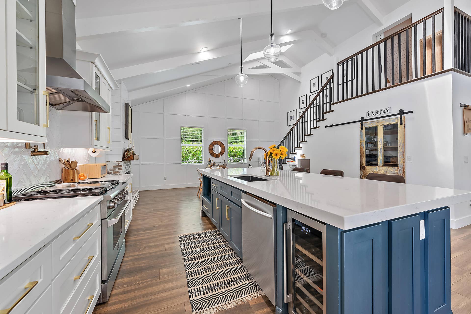 6204 SAND PINE Court, Jupiter, Jupiter, FL 33458 Vaulted ceilings with exposed beams, wood-finish flooring, white cabinetry with gold-tone hardware, stainless steel appliances, and a central island with countertop seating and a built-in wine refrigerator