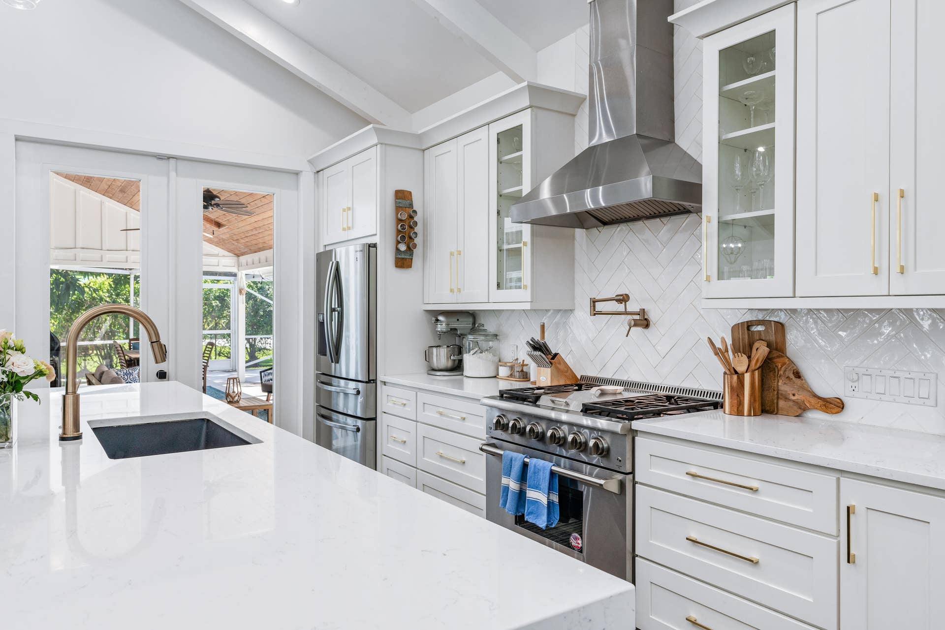 6204 SAND PINE Court, Jupiter, Jupiter, FL 33458 Bright kitchen featuring white cabinetry, stainless steel appliances, a herringbone tile backsplash, an undermount sink with a brass-finish faucet, and substantial countertops