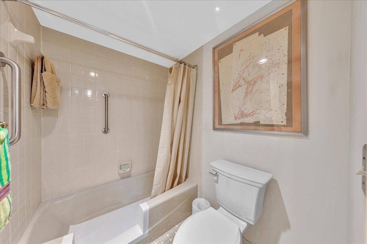 3520 Oaks Way, #904, Pompano Beach, FL 33069 The spacious primary suite offers added convenience and accessibility, with the bathtub modified for easier walk-in entry and additional grab bars.