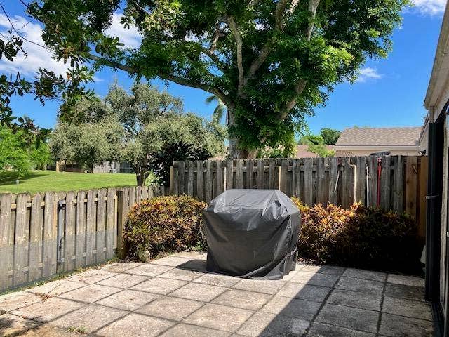 Fenced patio with grill and grass