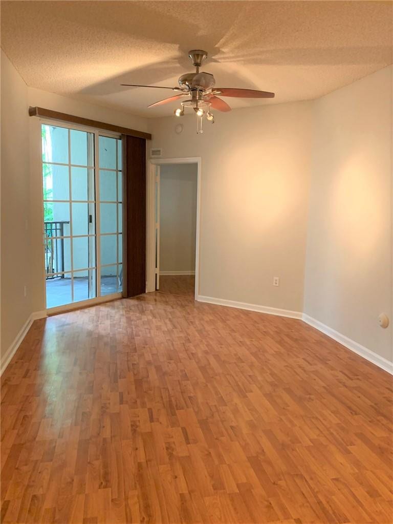 533 NE 3RD Avenue, #115, Fort Lauderdale, Fort Lauderdale, FL 33301 Spacious room showcasing warm wood-finish flooring, ceiling fan with integrated lighting, glass sliding doors opening to a balcony, and fresh neutral walls providing a blank canvas for personalization