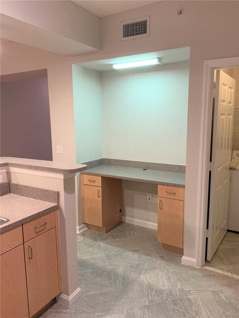 533 NE 3RD Avenue, #115, Fort Lauderdale, Fort Lauderdale, FL 33301 Built-in desk with light wood-finish cabinetry, speckled countertop, and overhead task lighting