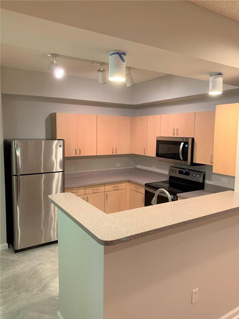 533 NE 3RD Avenue, #115, Fort Lauderdale, Fort Lauderdale, FL 33301 Kitchen featuring wood-finish cabinetry, stainless steel appliances, speckled countertops, a breakfast bar, and track lighting