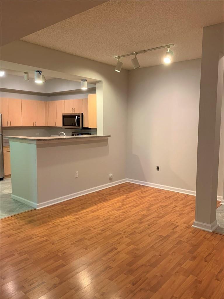 533 NE 3RD Avenue, #115, Fort Lauderdale, Fort Lauderdale, FL 33301 Open-concept living and dining area featuring warm wood-finish flooring, recessed and track lighting throughout, and a half-wall kitchen peninsula with light blue cabinetry and stainless steel appliances