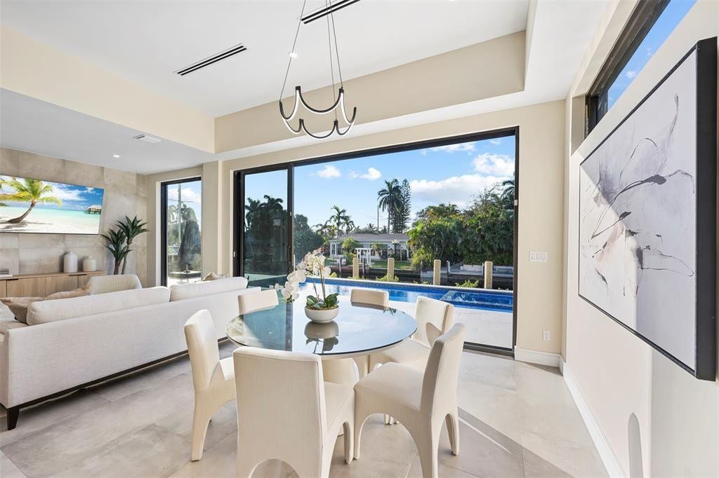 1212 AVOCADO Isle, Fort Lauderdale, Fort Lauderdale, FL 33315 Open-concept living space featuring large format tile flooring, a contemporary linear chandelier, and expansive sliding glass doors leading to a private pool and waterway