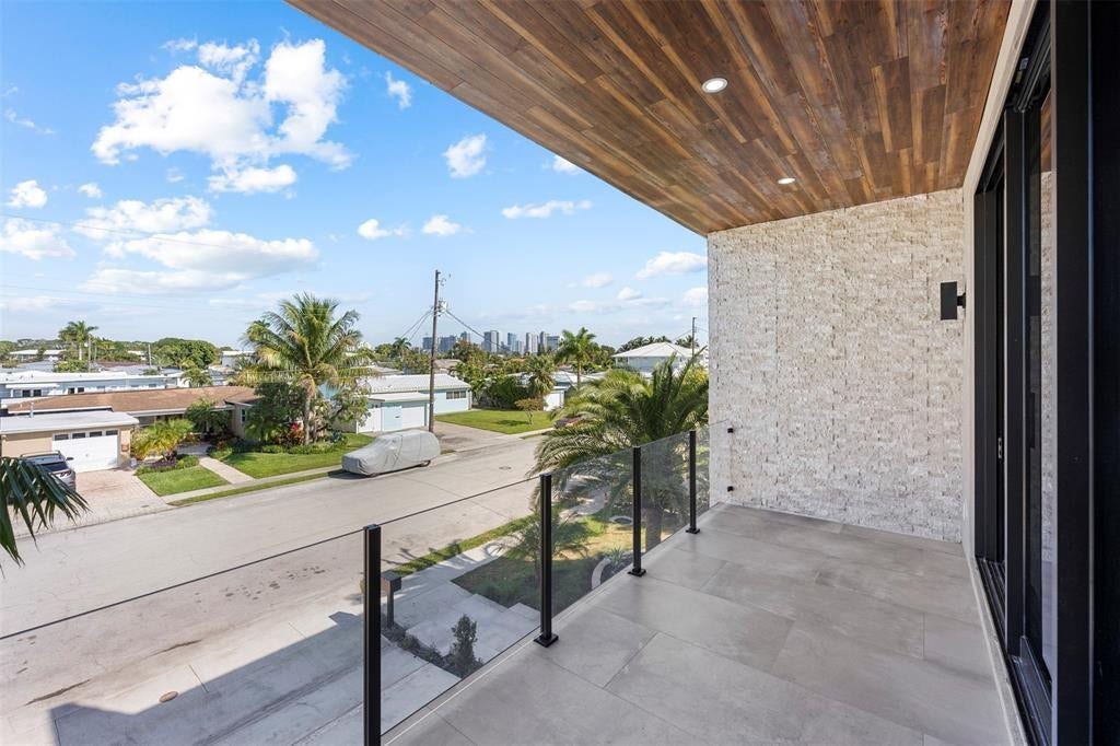 1212 AVOCADO Isle, Fort Lauderdale, Fort Lauderdale, FL 33315 Balcony featuring glass railings, wood-finish ceiling, tile flooring, stone-finish wall, and black-framed sliding door
