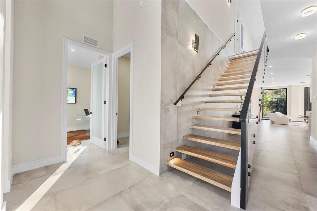 1212 AVOCADO Isle, Fort Lauderdale, Fort Lauderdale, FL 33315 Modern floating staircase with wood-finish treads and a glass railing with a black metal handrail