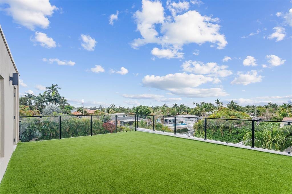 1212 AVOCADO Isle, Fort Lauderdale, Fort Lauderdale, FL 33315 Expansive rooftop terrace with artificial turf, glass panel railing, and exterior wall sconce