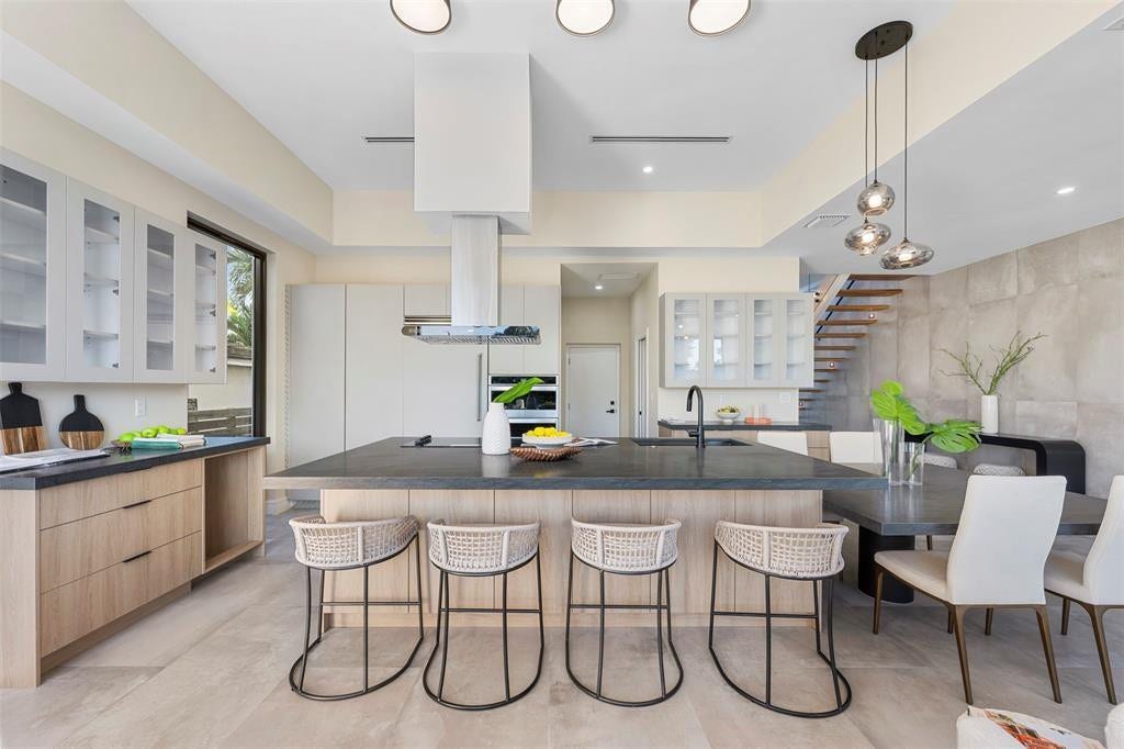 1212 AVOCADO Isle, Fort Lauderdale, Fort Lauderdale, FL 33315 Open-concept kitchen with a large island, wood-finish cabinetry, integrated stainless steel appliances, and a modern range hood