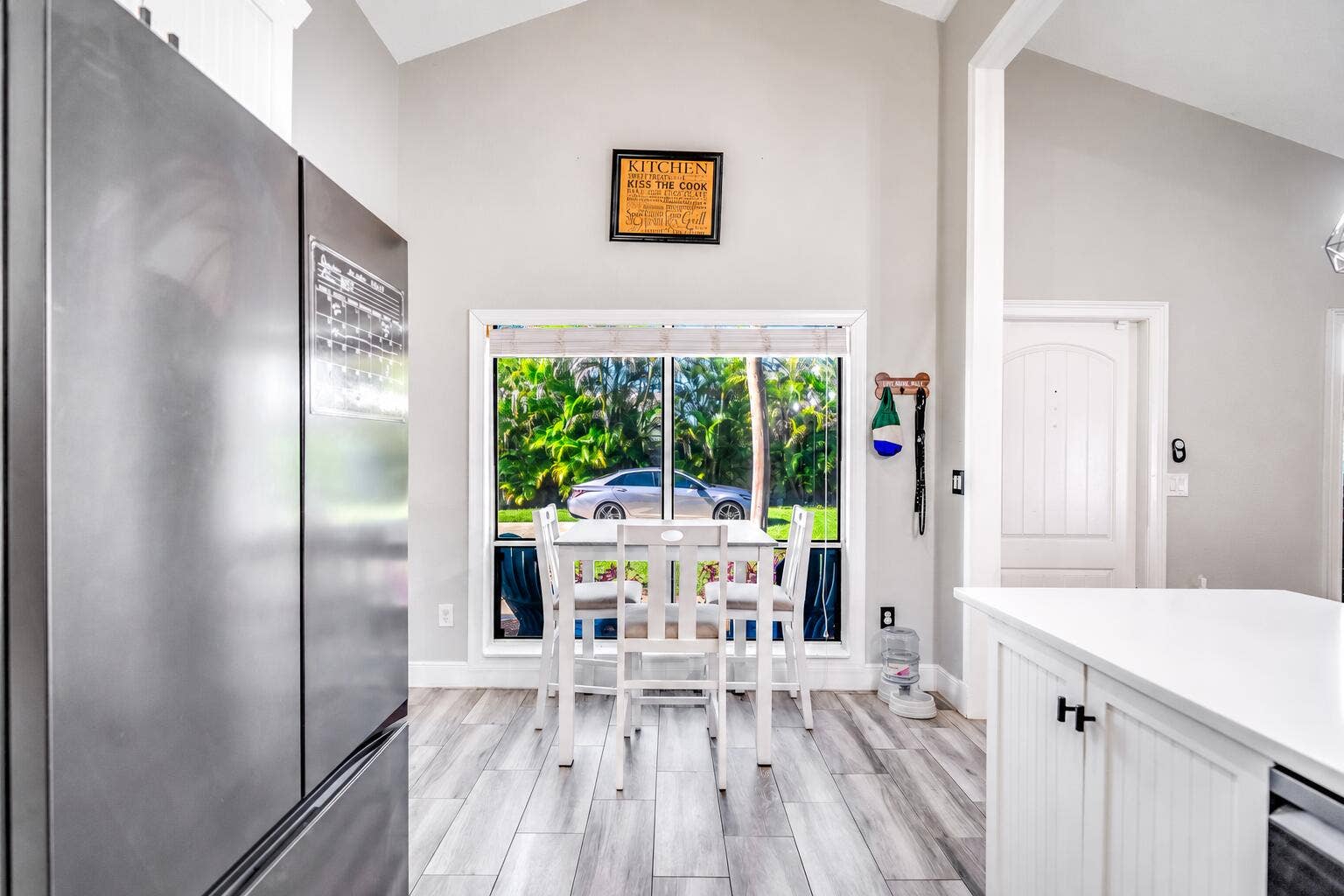 Vaulted ceiling with light gray walls, wood-finish flooring, and a large window