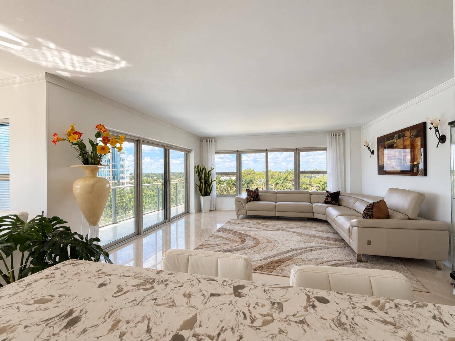 Expansive living space featuring a polished tile floor, crown molding, and large sliding glass doors