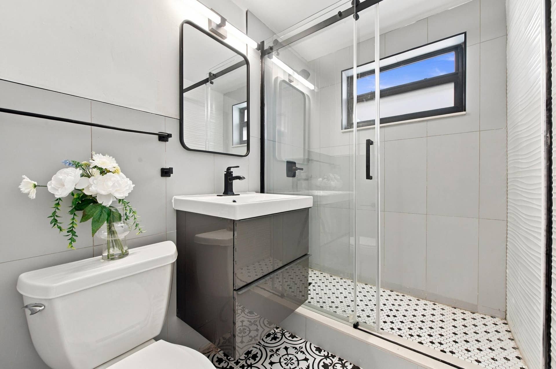 2536 GULFSTREAM Lane, Fort Lauderdale, FL 33312 Modern vanity with matte black faucet, walk-in shower with patterned tile, glass shower door, and horizontal window