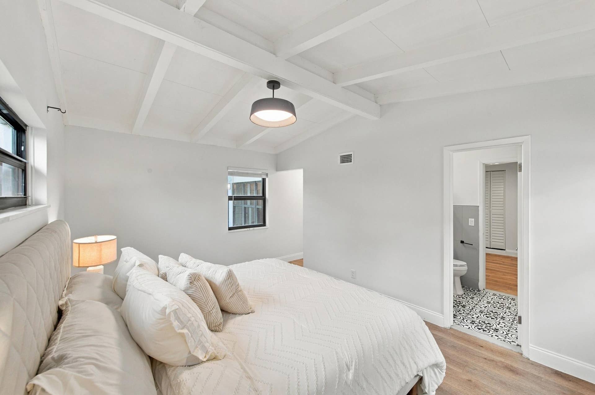 2536 GULFSTREAM Lane, Fort Lauderdale, FL 33312 Vaulted ceiling with exposed beams, wood-finish flooring, recessed window, and an attached bathroom with patterned floor tile and a half-wall of rectangular gray tiles