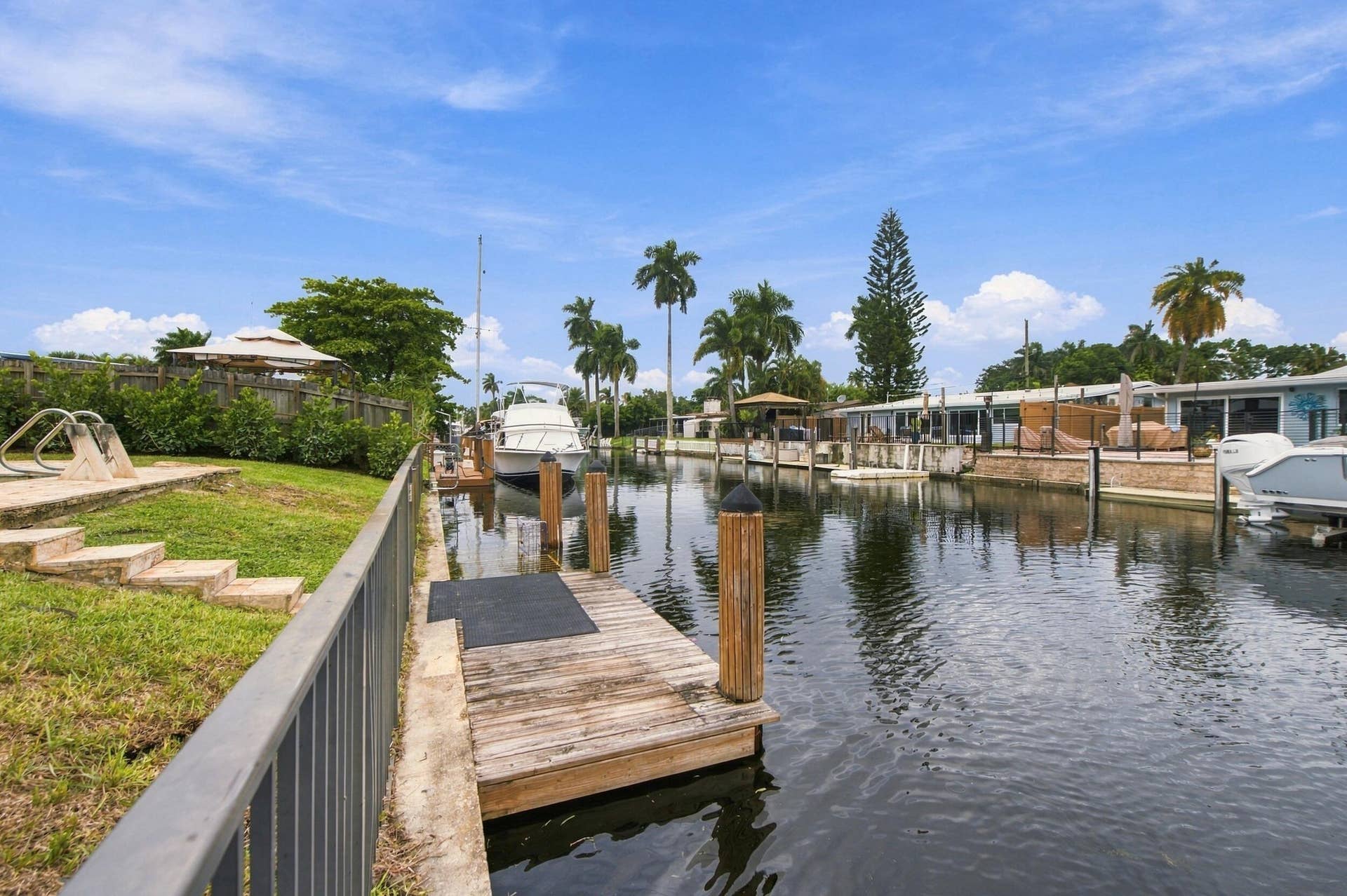 2536 GULFSTREAM Lane, Fort Lauderdale, FL 33312 Waterfront property with a private dock, featuring a manicured lawn and mature palm trees