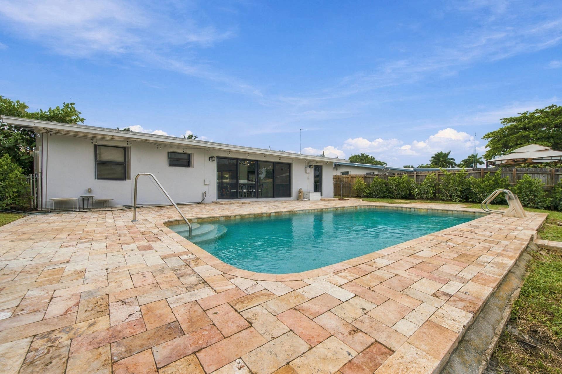 2536 GULFSTREAM Lane, Fort Lauderdale, FL 33312 Expansive backyard featuring a swimming pool, surrounding paver patio, sliding glass doors, and a privacy fence