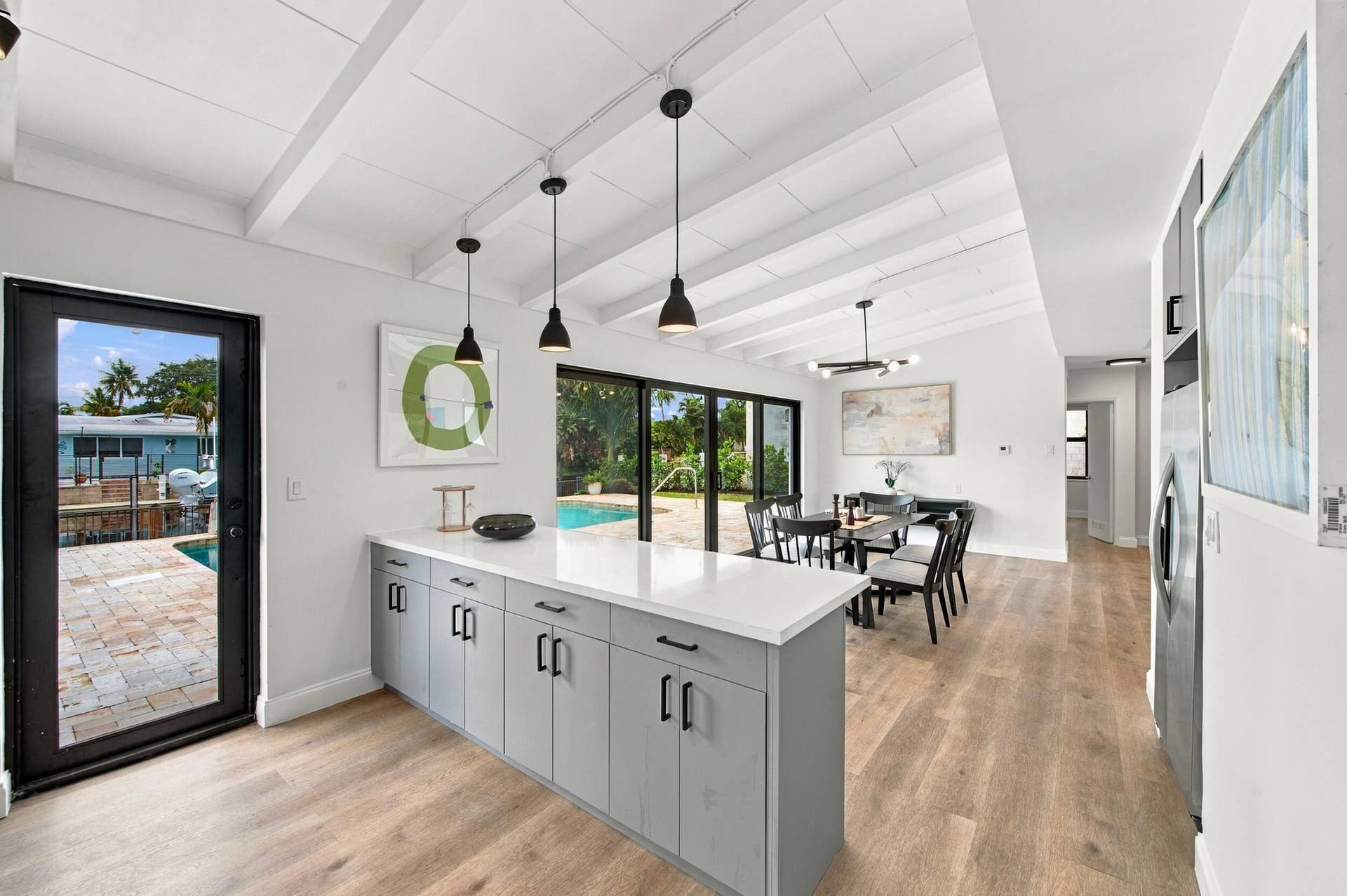 2536 GULFSTREAM Lane, Fort Lauderdale, FL 33312 Vaulted ceilings with exposed beams, wood-finish flooring, and a kitchen island with light gray cabinetry and a white countertop