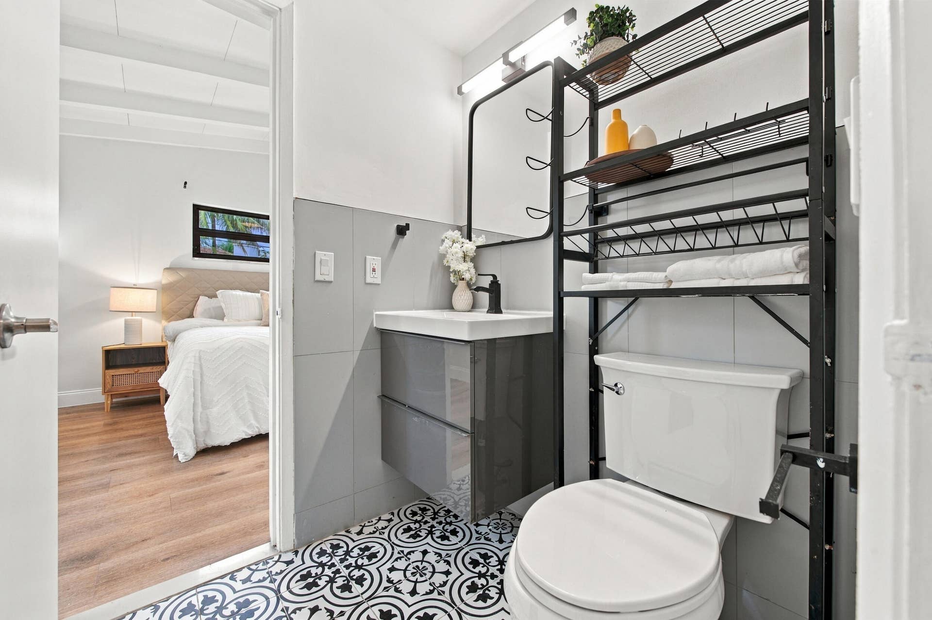 2536 GULFSTREAM Lane, Fort Lauderdale, FL 33312 Patterned floor tile, wall-mounted vanity, black wall-mounted faucet, over-the-toilet shelving unit, and grey wall tiles