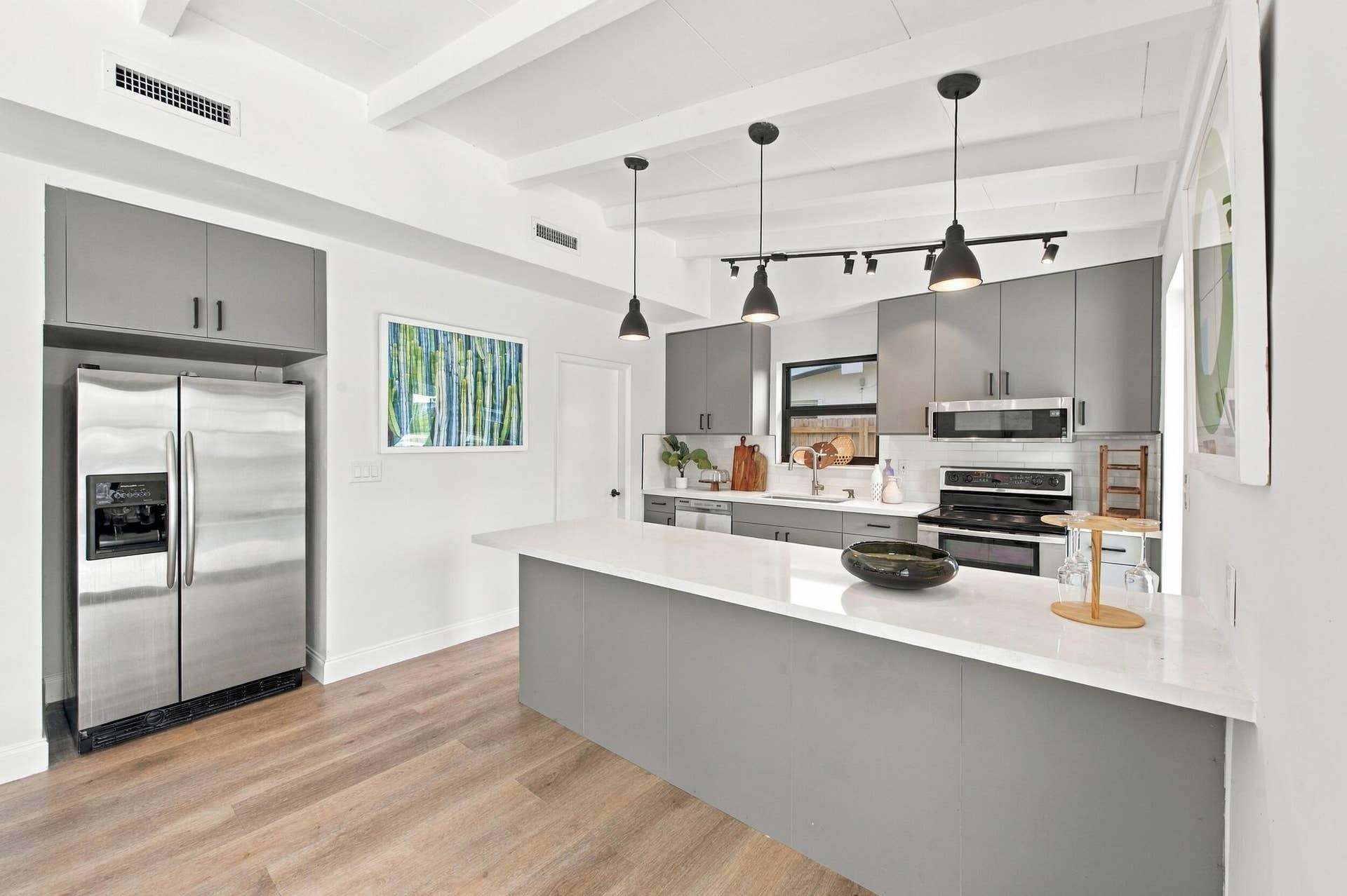 2536 GULFSTREAM Lane, Fort Lauderdale, FL 33312 Modern kitchen featuring wood-finish flooring, white exposed beam ceiling, gray cabinetry, stainless steel appliances, and a central island with a white countertop