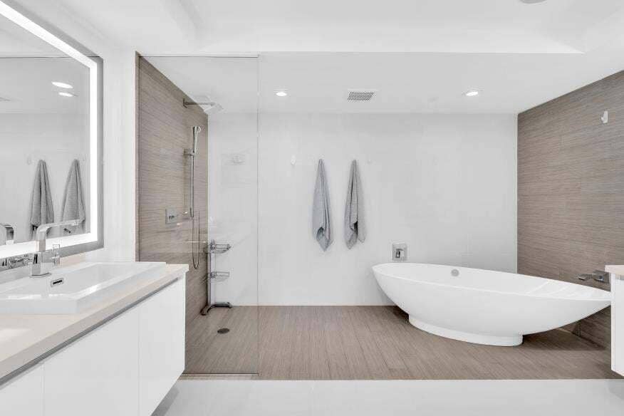 Sunny Isles Beach, Sunny Isles Beach, FL 33160 Modern bathroom with a freestanding soaking tub, glass-enclosed shower, wood-finish flooring, and a vanity with an illuminated mirror