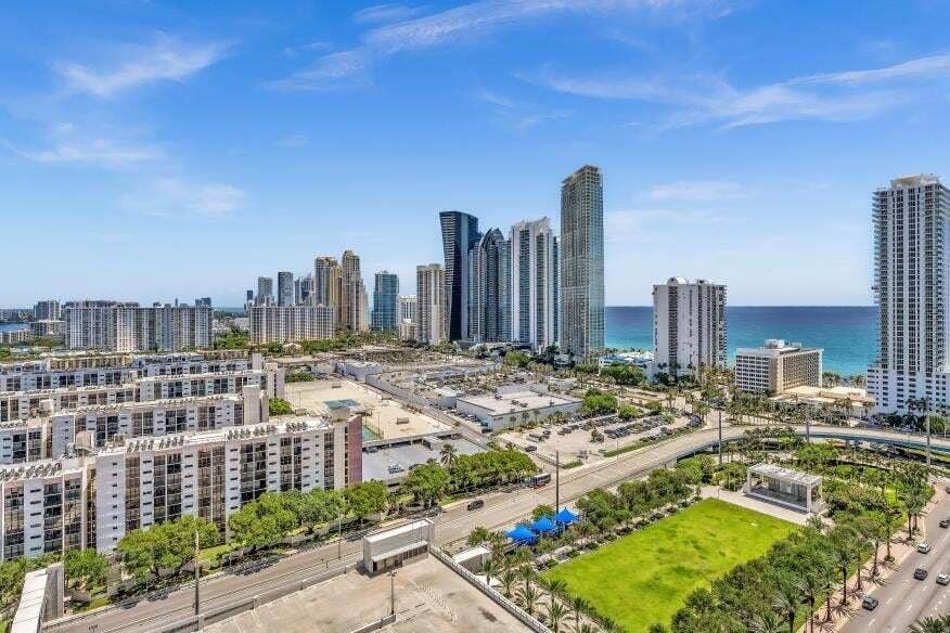 Sunny Isles Beach, Sunny Isles Beach, FL 33160 Expansive urban landscape featuring high-rise buildings, distant ocean, and a green space with mature trees