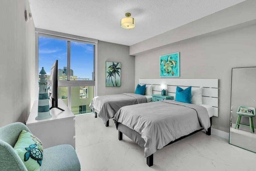 Sunny Isles Beach, Sunny Isles Beach, FL 33160 Expansive window with city background, overhead ceiling light fixture, white headboards, and light-toned flooring